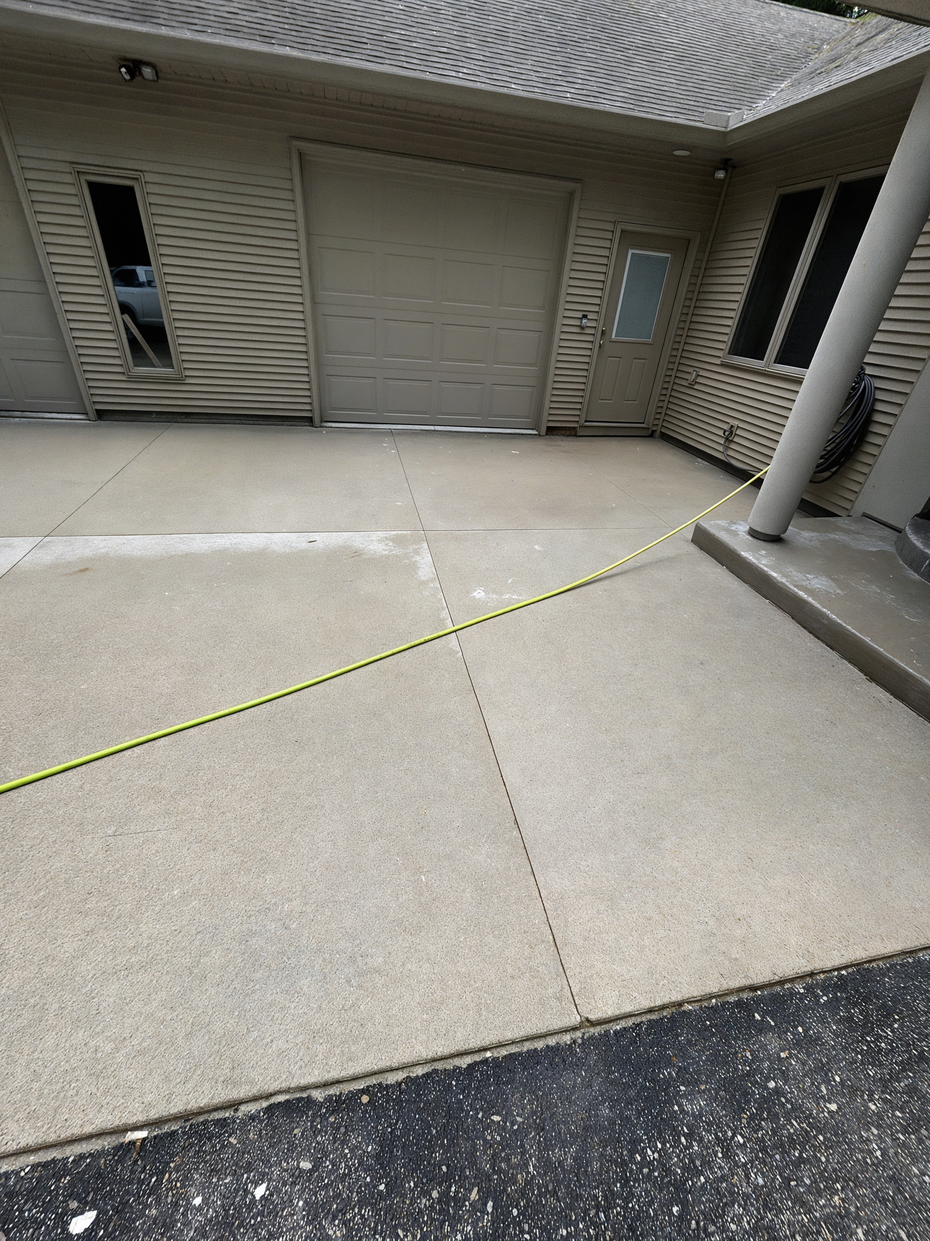 After: driveway cleaned with surface cleaner, near garage