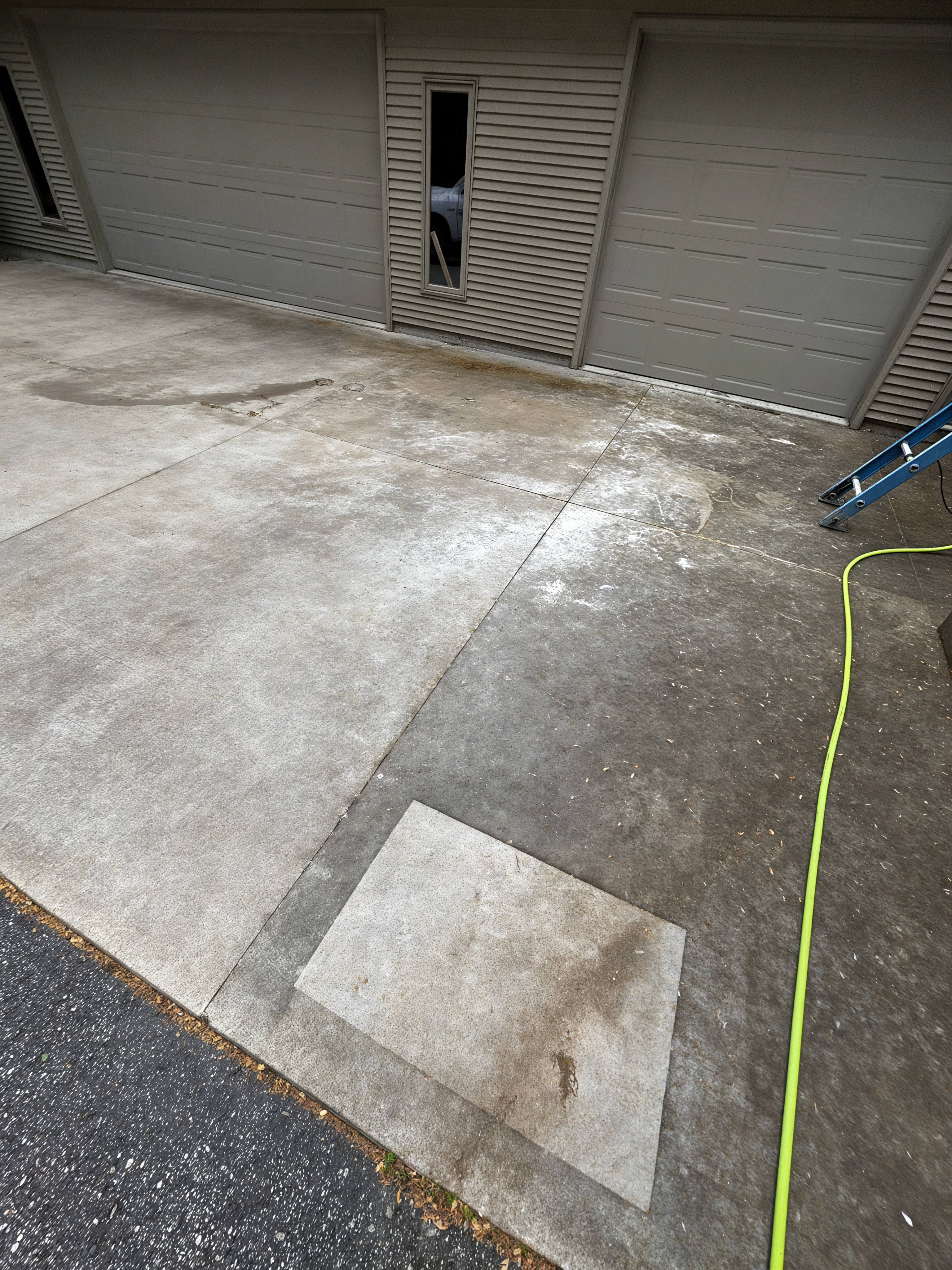Before: driveway with dark staining and test patch visible